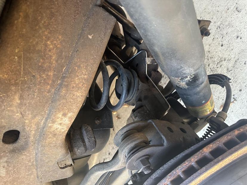 Coil spring and shock absorber on a steering knuckle with the brake rotor