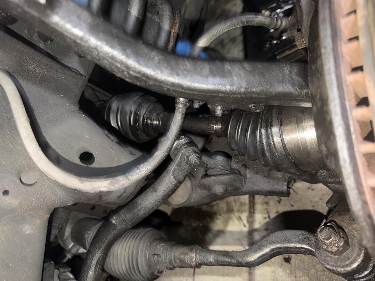 Close-up of CV axle boots, tie rod ends, and steering components during drivetrain service