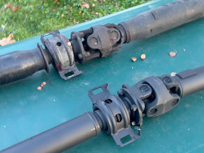 Two driveshafts on a table, centre bearings and U-joints close up