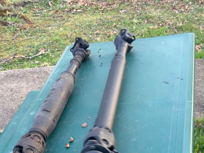 Two driveshafts side by side on a table outdoors