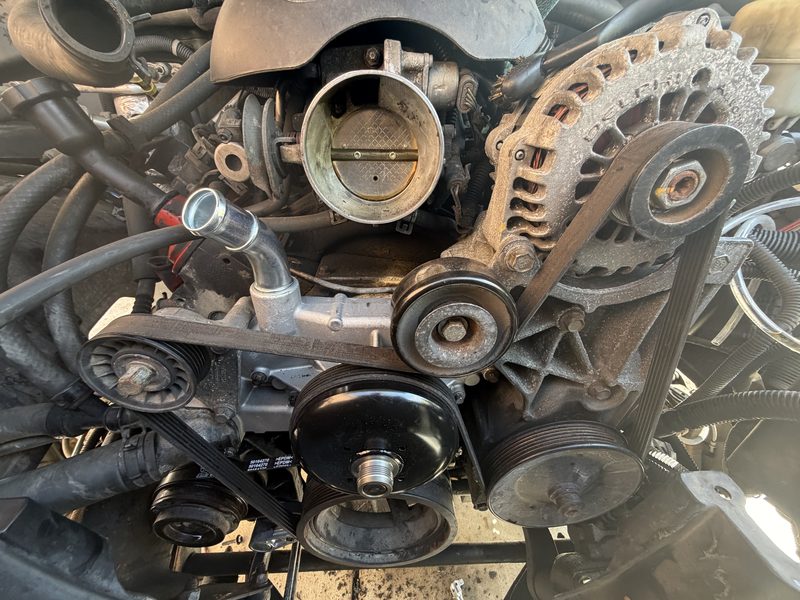 Engine front showing pulleys, throttle body, and serpentine belt system
