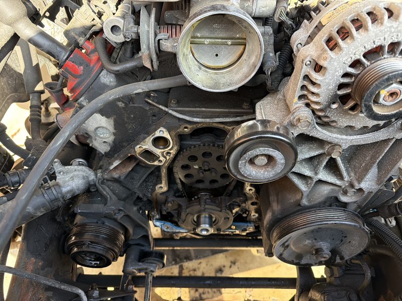 Engine front with timing cover, pulleys, and alternator exposed during engine swap