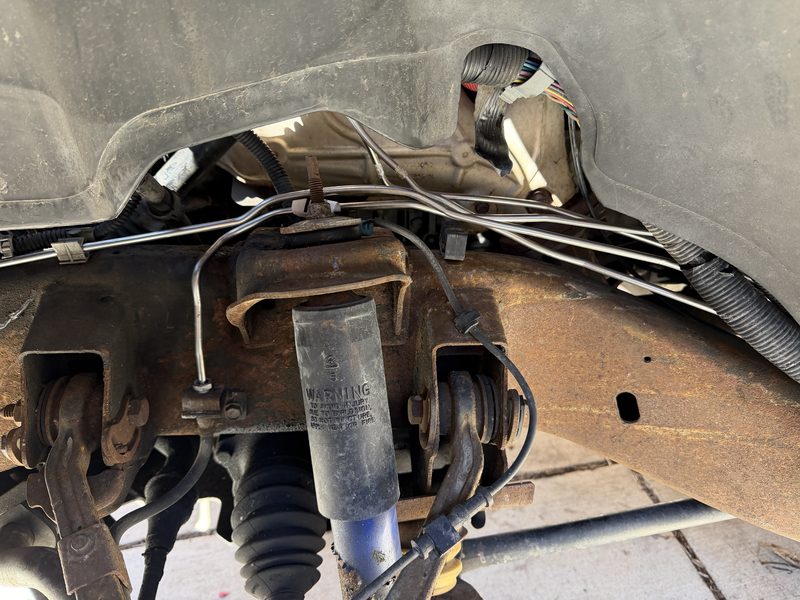 Front suspension assembly with shock, spring, and brake lines visible