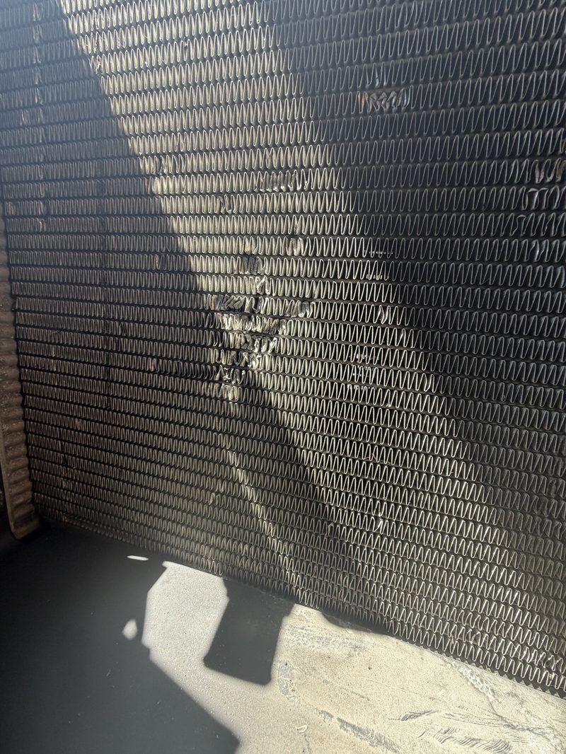 Damaged radiator with visible corrosion and leak points during cooling system repair