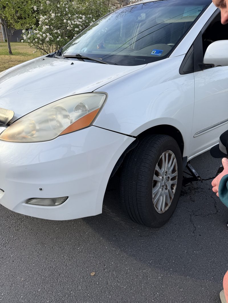 White sedan receiving roadside tire service