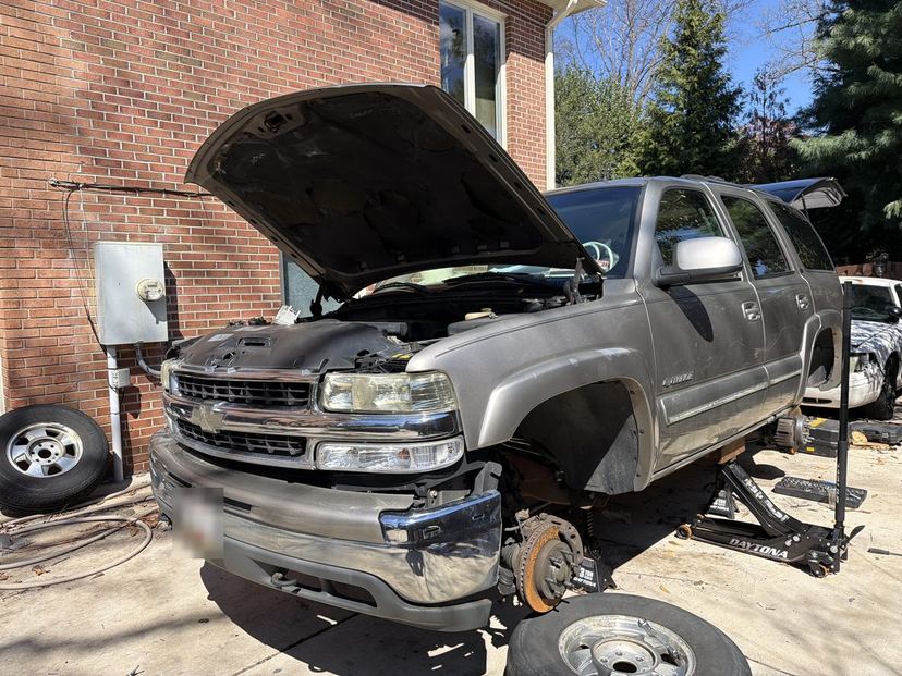 Chevrolet SUV in a driveway with the hood open and a front wheel removed for on-site service