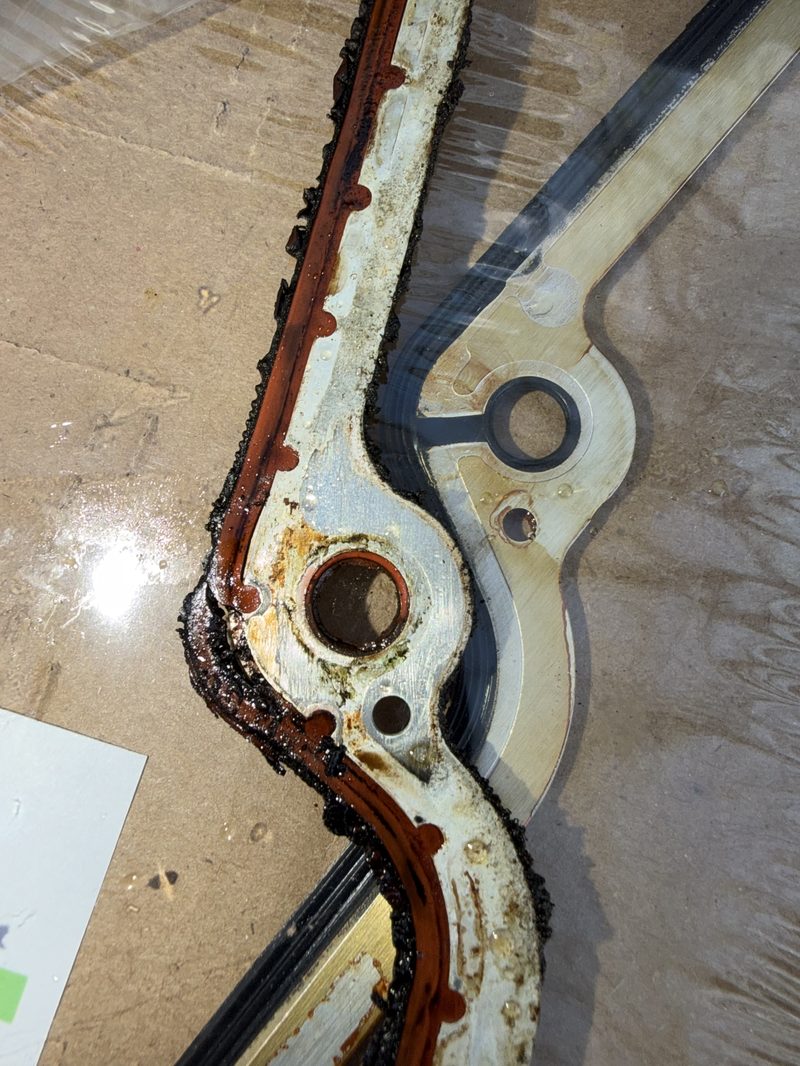 Old timing cover gasket with hardened sealant beside the new gasket